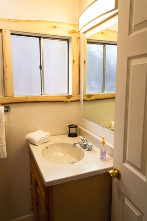 Bathroom features a sink, mirror, and window with a towel nearby.