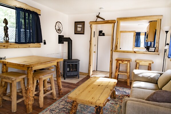 Cozy communal dining area with a central table and stools, a wood-burning stove, and a mirror.