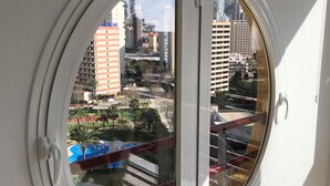 A round window with a view of a cityscape, including buildings and a park. - Cristian's Apartment 2 (Benidorm)