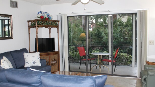 A living room with a sofa, TV, and a dining area with chairs and a table. - 2bd, 2ba, 1st Floor Condo: Pool, Short Drive to Beach, Tennis, Lanai, Near IMG (Bradenton)