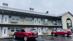Un motel de dos pisos con techo plano, numerosas ventanas y un estacionamiento techado.