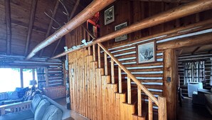 A wooden interior with a staircase, a sofa, and a dining area.