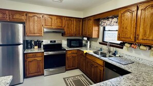 Una cucina con mobili in legno, elettrodomestici in acciaio inossidabile, piani in granito e un tappeto decorato.