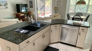 Une cuisine moderne dotée d’un plan de travail en granit, d’appareils électroménagers en acier inoxydable et d’un tapis noir.