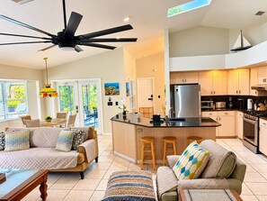 A modern kitchen with a central island, stainless steel appliances, and a dining area with a sofa and chairs. - ☀️🌴COASTAL BEAUTIFUL  Pool Home (1800 Sq/ft) All to Yourself! * (Vero Beach)