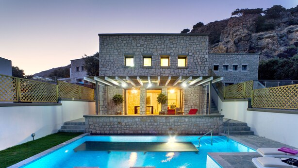 Edifici de pedra amb piscina, zones d'estar a l'exterior i una escala que condueix a un balcó.