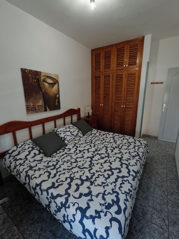 A bedroom with a bed, a nightstand, a lamp, a wooden wardrobe, and a wall-mounted painting. - Apartment with sea views in Los Cristianos beach (Los Cristianos)