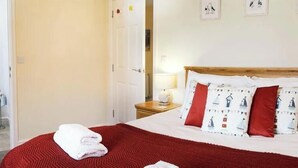 A hotel room with a bed, a red blanket, and a white towel on the bed.