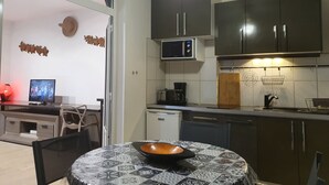 A modern kitchen with dark cabinets, a microwave, and a dining area with a table and chairs. - Hibiscus beach and pool Sainte-Luce Martinique (Sainte-Luce)