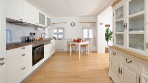 Uma cozinha com armários brancos, bancada de madeira e um espaço de refeições com mesa e cadeiras.