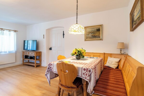 Une pièce chaleureuse avec un lit en bois, une table à manger ornée d’un vase de fleurs, un téléviseur et une lampe.