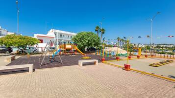 Explore a vibrant public park with play structures, benches, and palm trees.