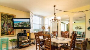 A dining area with a large table, multiple chairs, a television, and a painting of a tropical scene. - 3/2 condo Futura Yacht Club Pool, Dockage, Wifi, dockage, beach (Islamorada)