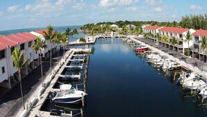 A marina with boats docked, a bridge, and buildings with red roofs. - 3/2 condo Futura Yacht Club Pool, Dockage, Wifi, dockage, beach (Islamorada)