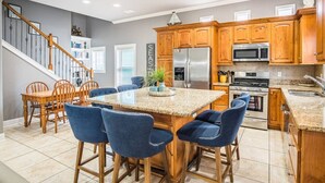 A kitchen with wooden cabinets, a granite countertop, and a stainless steel refrigerator.