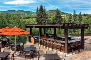 Un patio exterior con una zona de bar, asientos y una pérgola.