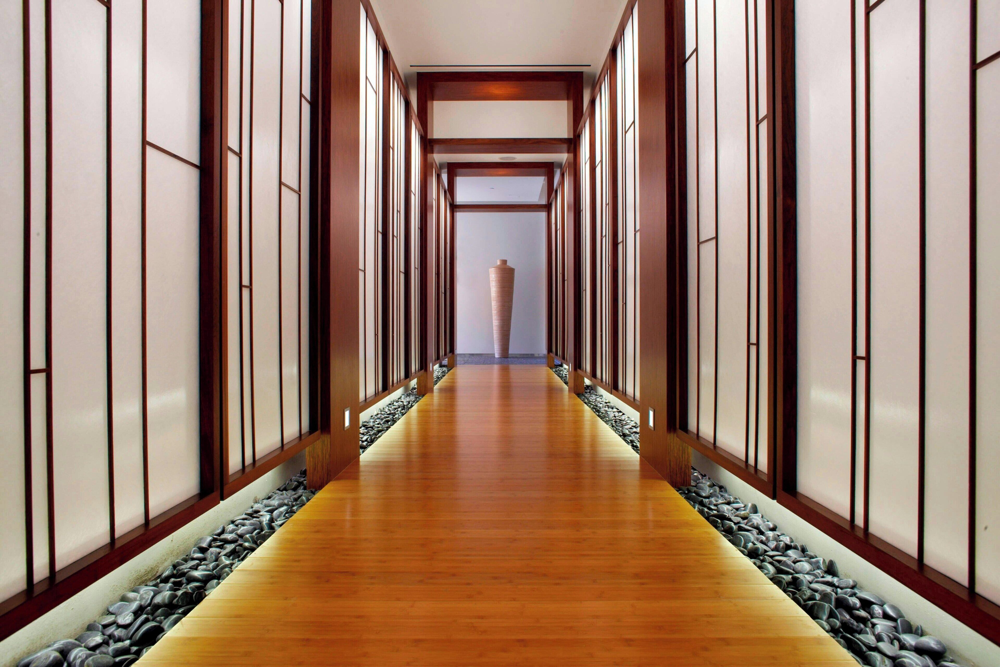 A hallway with wooden flooring, stone accents, and traditional sliding doors.