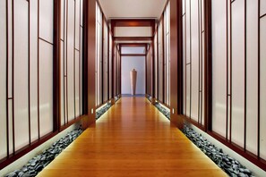 Un couloir doté d’un plancher en bois, de quelques éléments décoratifs en pierre et de portes coulissantes traditionnelles.