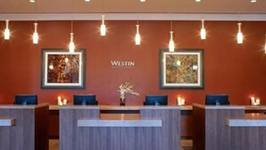A reception area with a modern design, featuring a wooden reception desk, framed artwork on the wall, and a vase with flowers. - The Westin Riverfront Resort & Spa, Avon, Vail Valley (Avon)