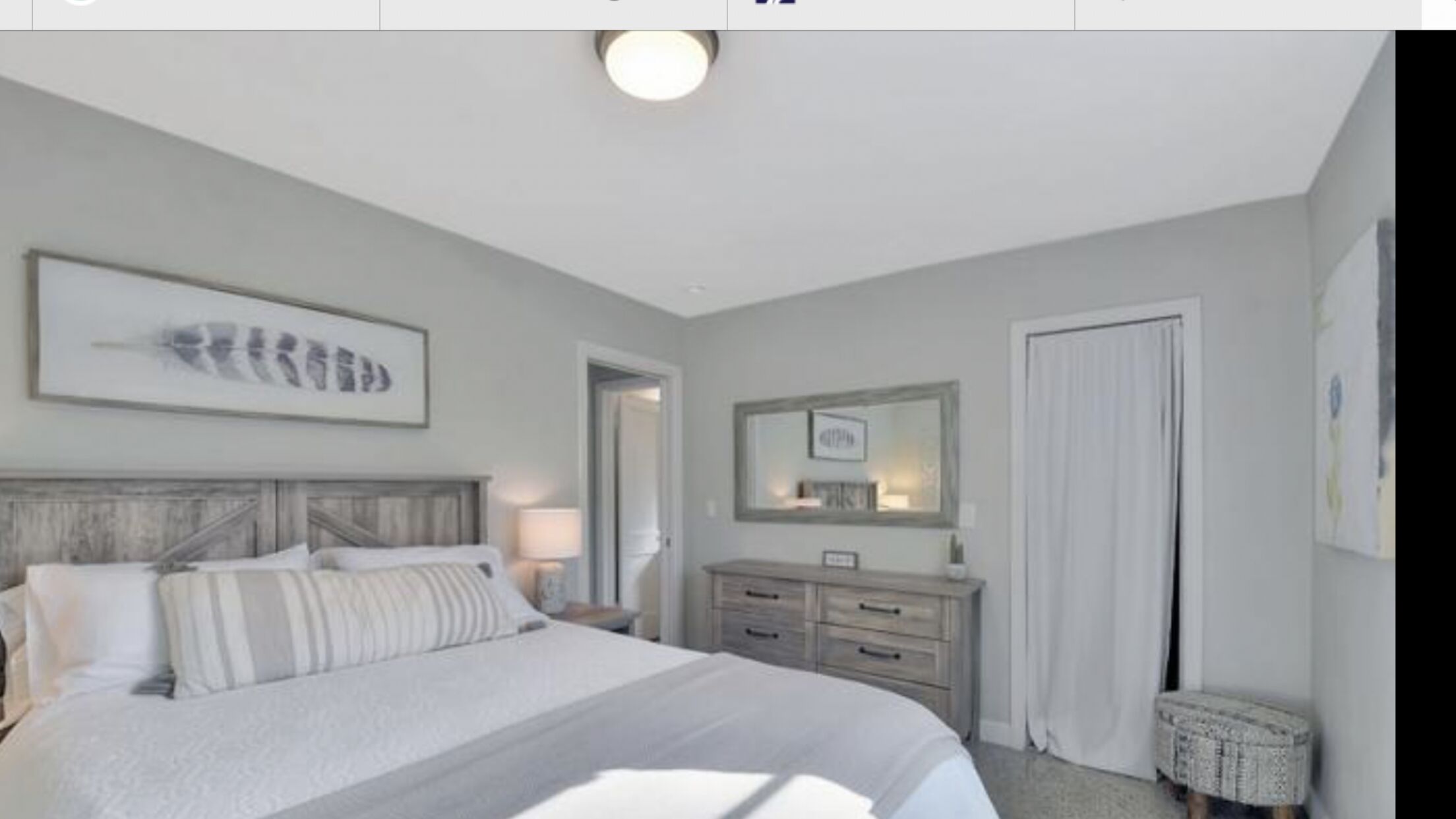 Een slaapkamer met een groot bed, een dressoir, een spiegel en een deur.
