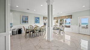 A spacious dining area with a marble floor, elegant furniture, and artwork on the walls. - Pineapple Palace, Luxury Oceanfront Beach House with Pool and Hot Tub (North Myrtle Beach)