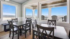 Un comedor con vistas a la playa, que incluye una mesa, sillas y un banco.