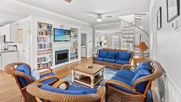 A spacious living room with wicker furniture, a fireplace, and a large bookshelf.