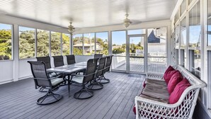 A covered outdoor area with a table and chairs, large windows, and a view of the surrounding area.
