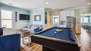 Une table de billard dans une pièce comprenant un canapé, un téléviseur et un coin cuisine.