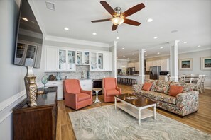 A spacious living room with a sofa, chairs, a coffee table, and a ceiling fan.