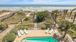 Un espace piscine offrant une vue sur la plage et l’océan.