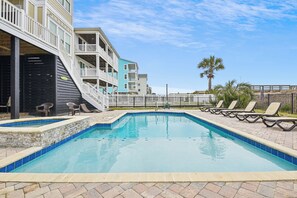 A swimming pool with lounge chairs, a staircase leading to a building, and a palm tree in the background.