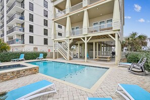 A multi-story building with a pool area, including a covered deck and lounge chairs. - Sun Sand & Sea, an Oceanfront 9BR House with Private Pool. (North Myrtle Beach)