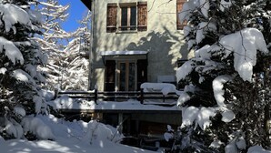 Un edificio cubierto de nieve con un balcón y contraventanas de madera.