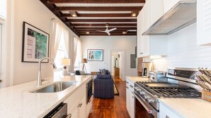 Une cuisine moderne dotée d’un îlot central, d’appareils électroménagers en acier inoxydable et d’un plafond en bois.