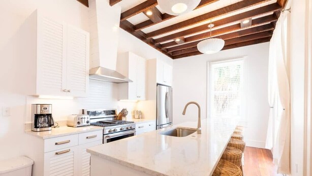 Une cuisine moderne avec des meubles blancs, des appareils en acier inoxydable et un plafond en bois.