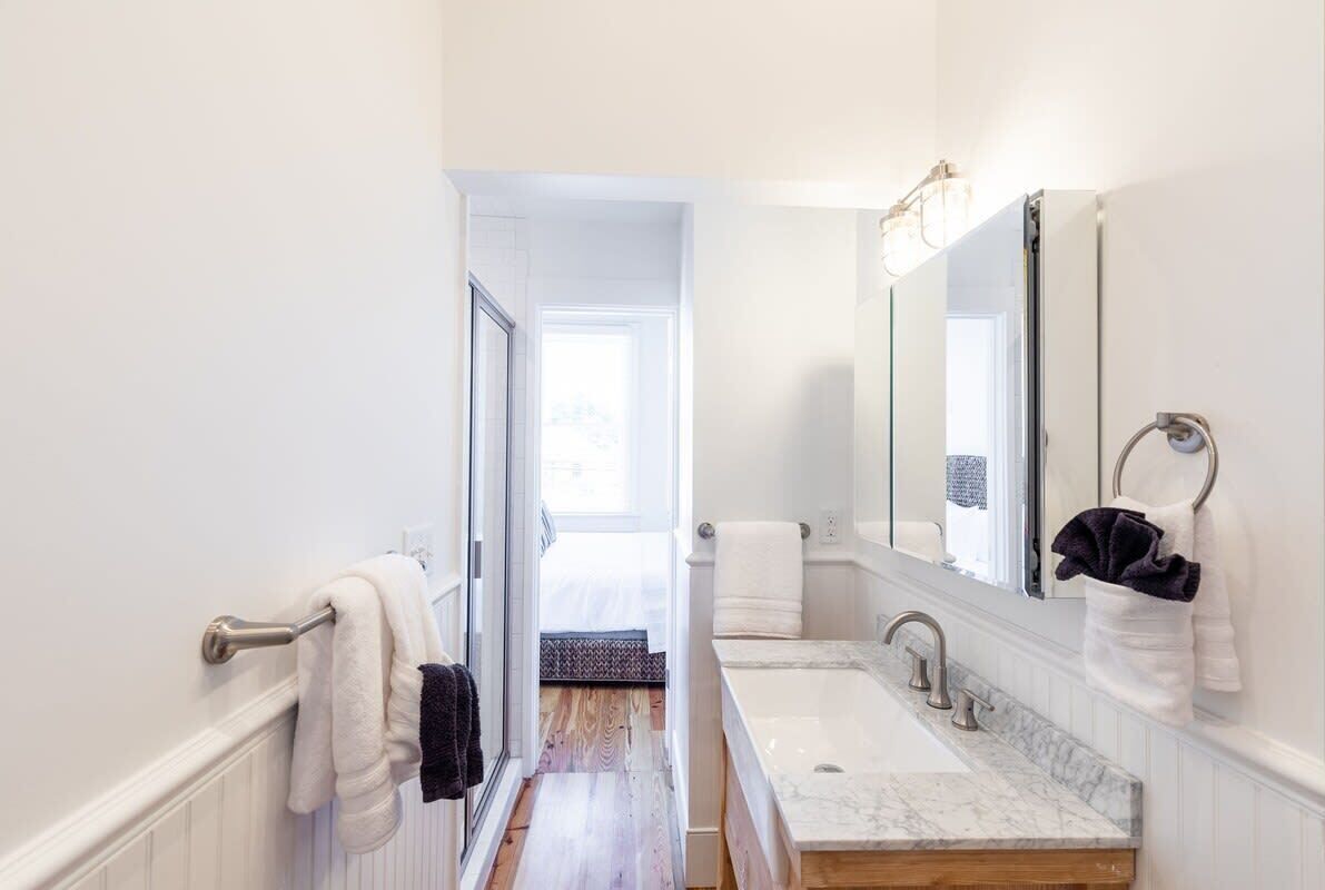 Un baño moderno con un espejo grande, una bañera y un lavamanos.