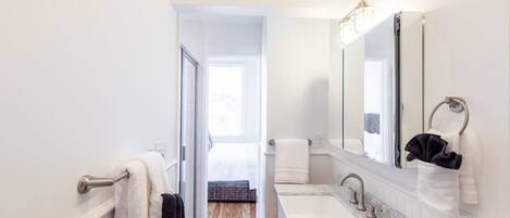 Un baño moderno con un espejo grande, una bañera y un lavamanos.