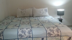 A bed with a patterned bedspread, two pillows, and a bedside lamp. - Luxury apartment playa azul cartagena 200m² (La Boquilla)