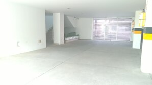 A spacious, empty room with a concrete floor, a staircase, and a large window with blinds. - Luxury apartment playa azul cartagena 200m² (La Boquilla)
