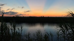 A calm body of water reflecting the sky during sunset. - Paradise on the Bayou at the Bat Cave! (Slidell)