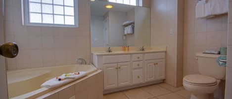 A bathroom with a bathtub, a sink, a toilet, and a large mirror.