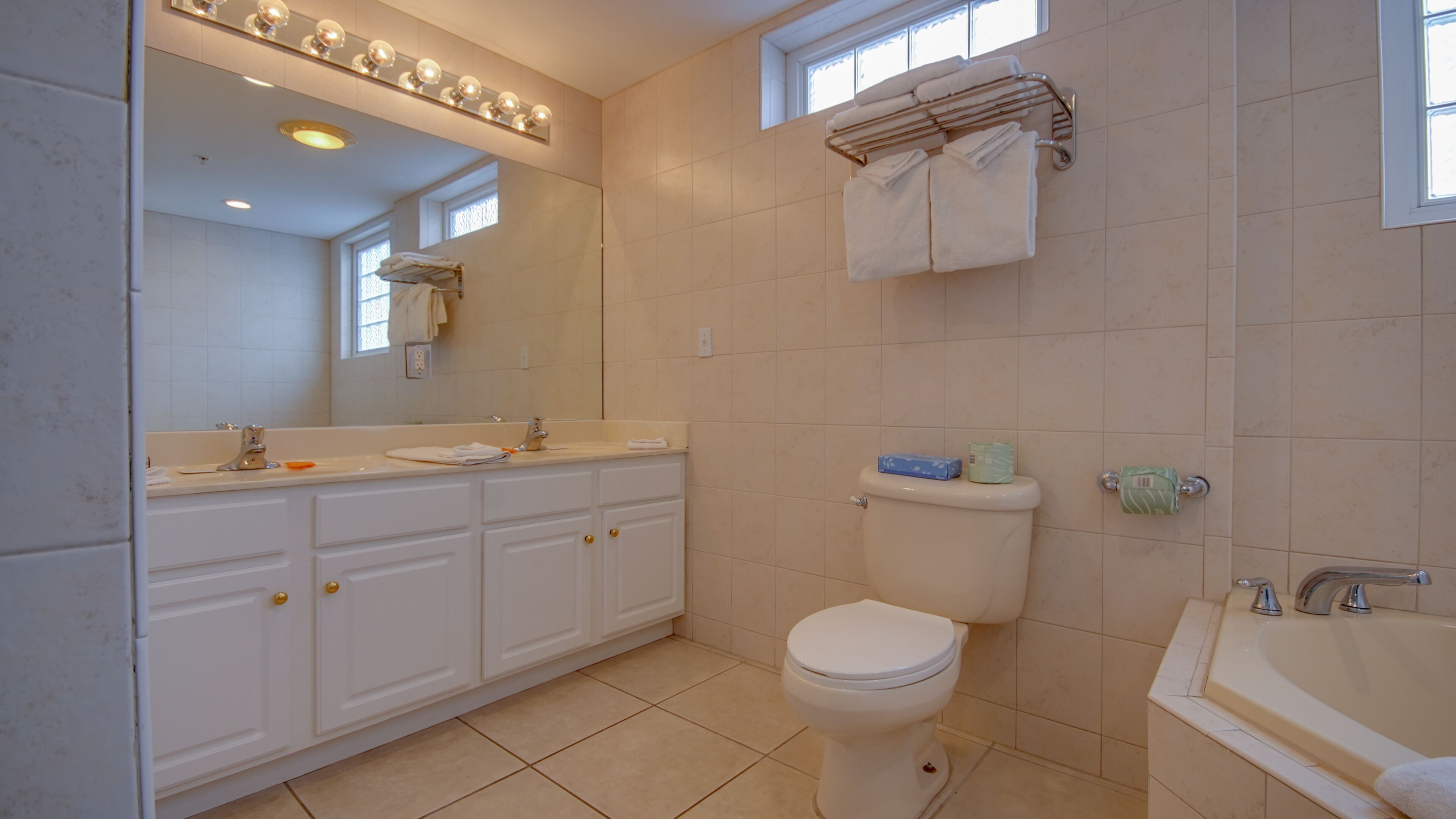 A bathroom with a toilet, sink, and bathtub. There are towels and toiletries on the counter.