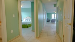 A hallway leading to a bedroom with a bed, a chair, and a lamp. - Americana Princess Suites and Condos (Ocean City)