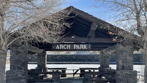 A stone pavilion with benches labeled "ARCH PARK" in a snowy setting.