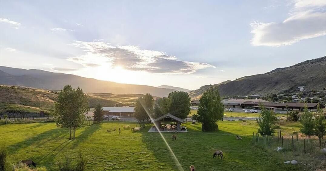 A rural landscape with a gazebo, open fields, and distant hills.