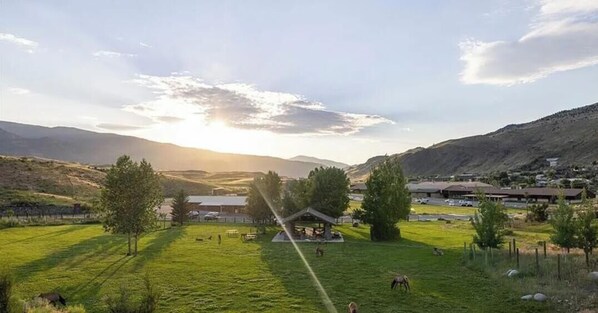 A rural landscape with a gazebo, open fields, and distant hills.