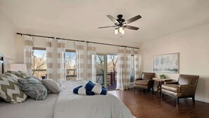 A bedroom with a large bed, a ceiling fan, a view to the outside, and a small table with chairs. - The Lakeview Retreat - Lake Access (Eureka Springs)