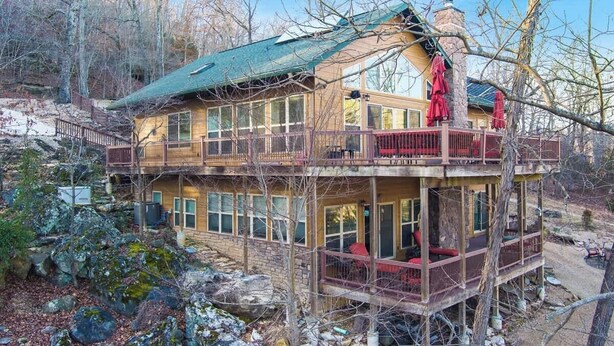 A multi-story log cabin with a balcony, surrounded by trees and rocks. - The Lakeview Retreat - Lake Access (Eureka Springs)