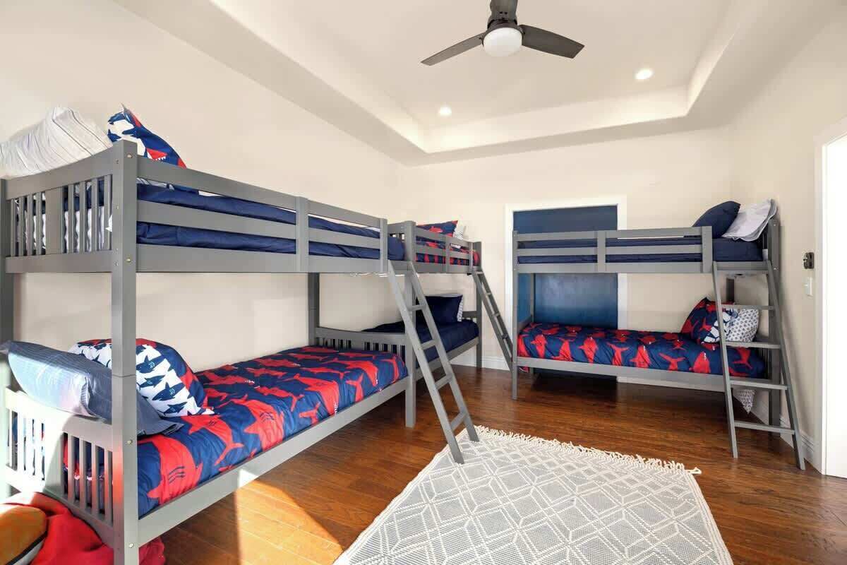 Une chambre avec des lits superposés, un ventilateur de plafond et un tapis à motifs géométriques.